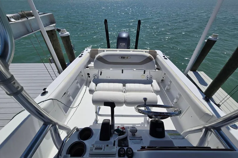 Slide: The Image of 2012 Sea Hunt Ultra 225 boat interior with steering wheel and seating, docked by the water. - 14