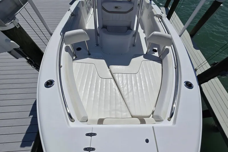 Slide: The Image of 2012 Sea Hunt Ultra 225 boat interior with white seating and deck, docked by water. - 15