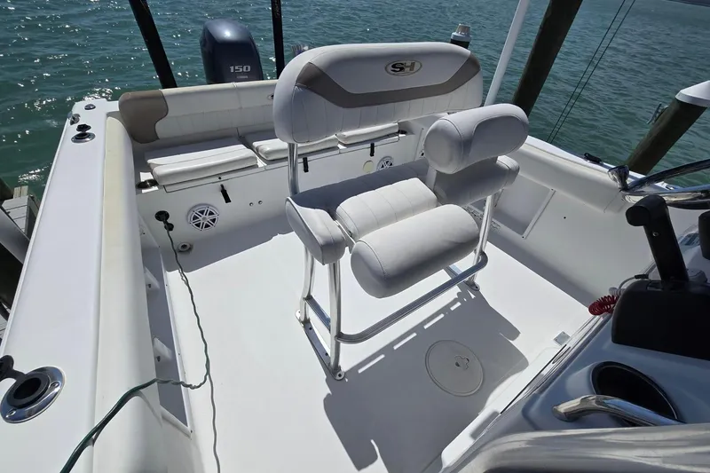Slide: The Image of 2012 Sea Hunt Ultra 225 boat interior with seating and steering, docked by the water. - 17