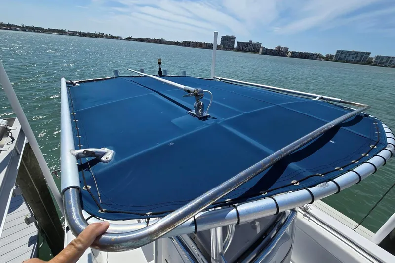 Slide: The Image of 2012 Sea Hunt Ultra 225 boat with blue canopy on calm water. - 20