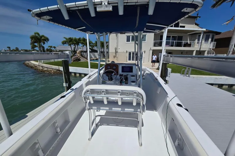 Slide: The Image of 2012 Sea Hunt Ultra 225 boat docked by waterfront home, featuring a spacious deck and canopy. - 6