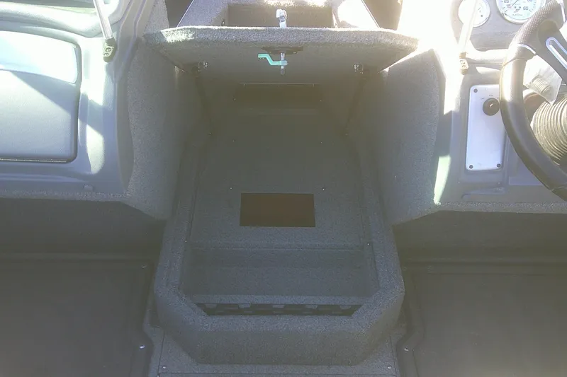 Slide: The Image of 2017 Lund 1875 Crossover XS boat interior, featuring storage compartment and dashboard controls. - 10