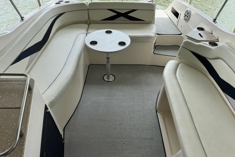 Slide: The Image of 2006 Rinker 282 Captiva Bowrider interior with seating and table, on calm water. - 14