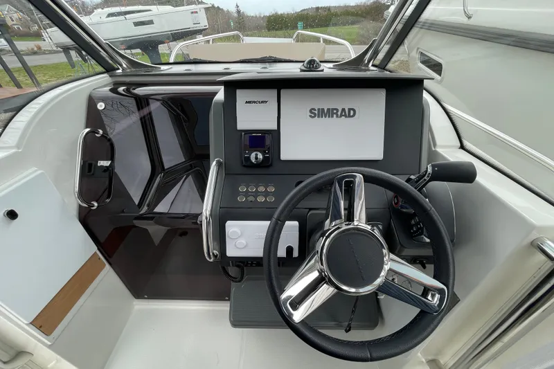Slide: The Image of 2023 Nimbus Tender 8 boat cockpit with steering wheel and Simrad navigation system. - 20