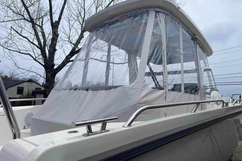 Slide: The Image of 2023 Nimbus Tender 8 boat with protective canopy, docked outdoors on a cloudy day. - 5