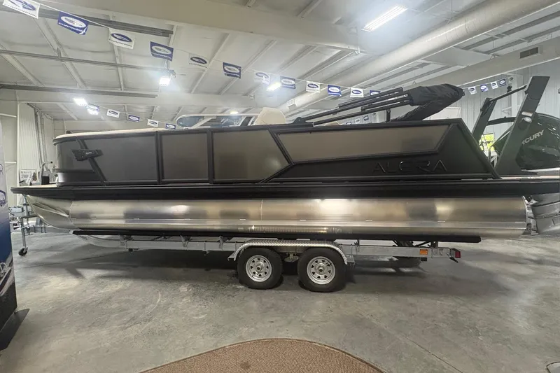Slide: The Image of 2026 Alera M25Q pontoon boat on trailer in indoor showroom. - 3