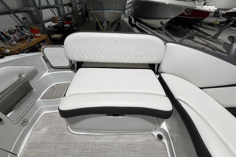 Slide: The Image of 2023 Crownline 280 SS boat interior with white cushioned seating in a showroom. - 14