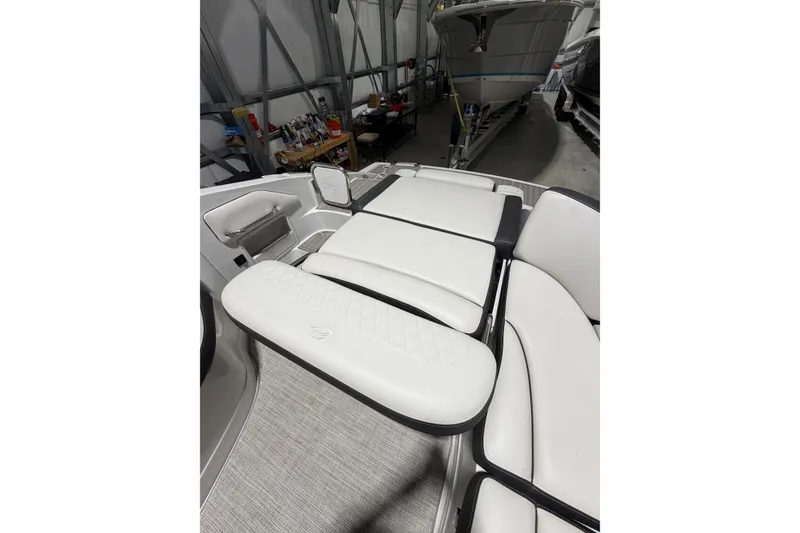 Slide: The Image of 2023 Crownline 280 SS boat interior with white cushioned seating in a storage facility. - 15