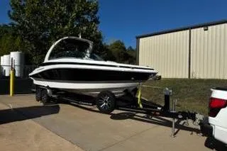 Slide: The Image of 2023 Crownline 280 SS boat on trailer, parked outdoors near a building. - 26