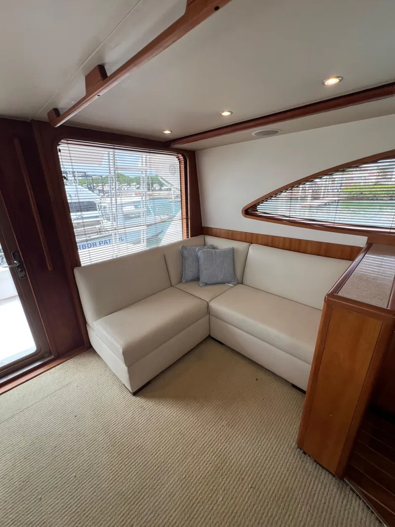 Slide: The Image of 2009 Bertram Convertible yacht interior with beige L-shaped sofa and wooden accents. - 11