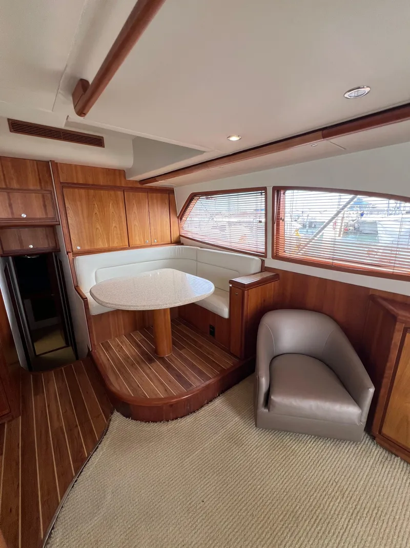Slide: The Image of 2009 Bertram Convertible yacht interior with wood paneling, dining area, and seating. - 12