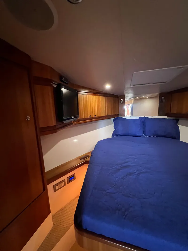 Slide: The Image of 2009 Bertram Convertible cabin interior with blue bedding and wooden cabinetry. - 22