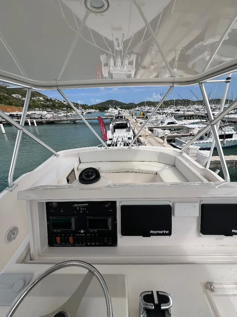 Slide: The Image of 2009 Bertram Convertible boat cockpit with marina view, featuring navigation equipment and steering wheel. - 5