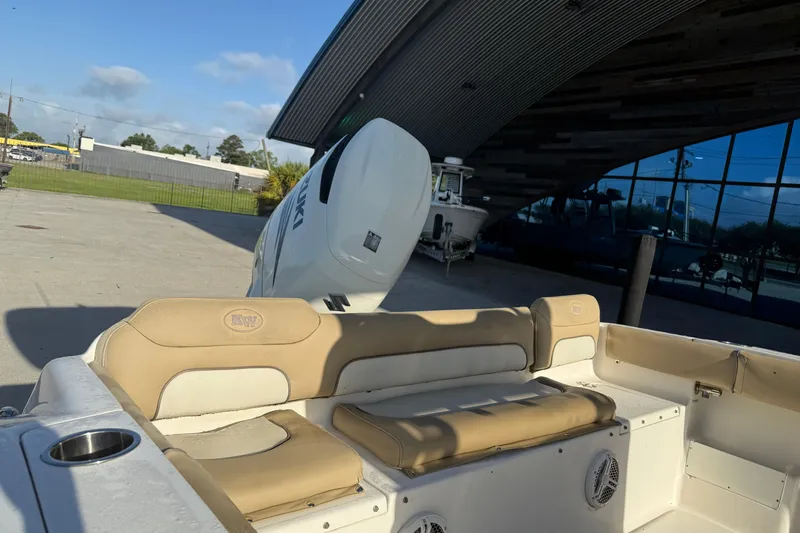 Slide: The Image of 2016 Key West 239 FS boat with Suzuki outboard motor, parked near a modern building. - 11