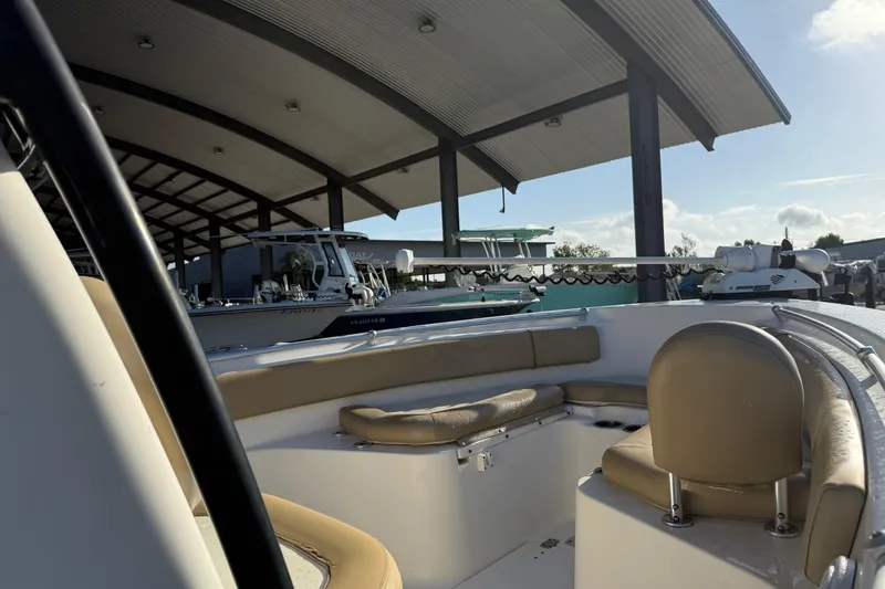 Slide: The Image of 2016 Key West 239 FS boat under covered dock, featuring tan seating and modern design. - 13