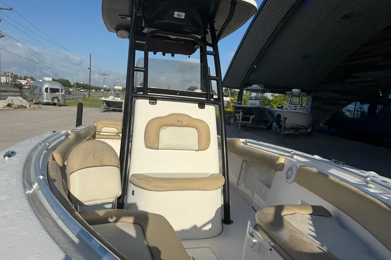 Slide: The Image of 2016 Key West 239 FS boat interior with beige seating and T-top in a marina setting. - 15