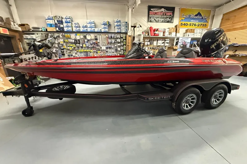 The Image of 2026 Skeeter ZX150 boat in showroom, red and black design, on a trailer. - 0