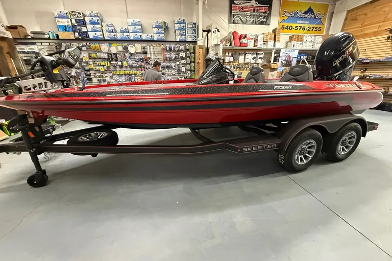 Slide: The Image of 2026 Skeeter ZX150 boat in showroom, red and black design, on a trailer. - 4