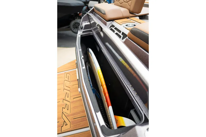 Slide: The Image of 2025 Supra SE 550 boat storage compartment with surfboards and cushioned seating. - 11