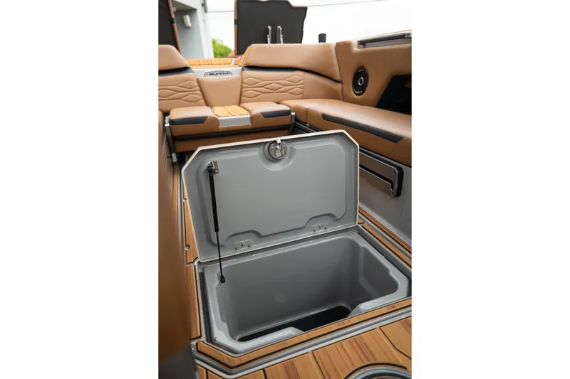 Slide: The Image of 2025 Supra SE 550 boat interior with open storage compartment, tan seating, and wood accents. - 22