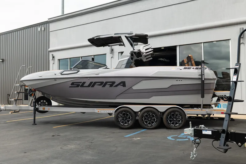 Slide: The Image of 2025 Supra SE 550 boat on trailer outside a building, showcasing sleek design. - 3
