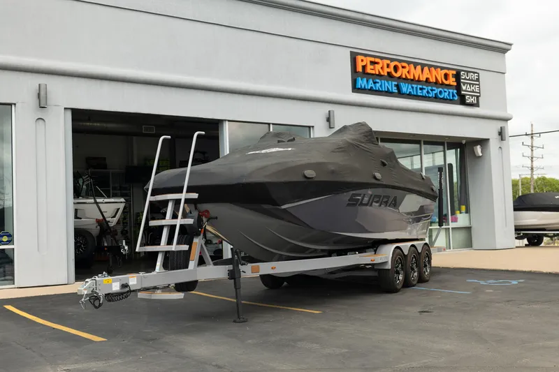 Slide: The Image of 2025 Supra SE 550 boat covered on trailer at Performance Marine Watersports dealership. - 40