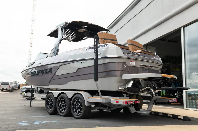 Slide: The Image of 2025 Supra SE 550 boat on trailer, parked outside a showroom. - 6