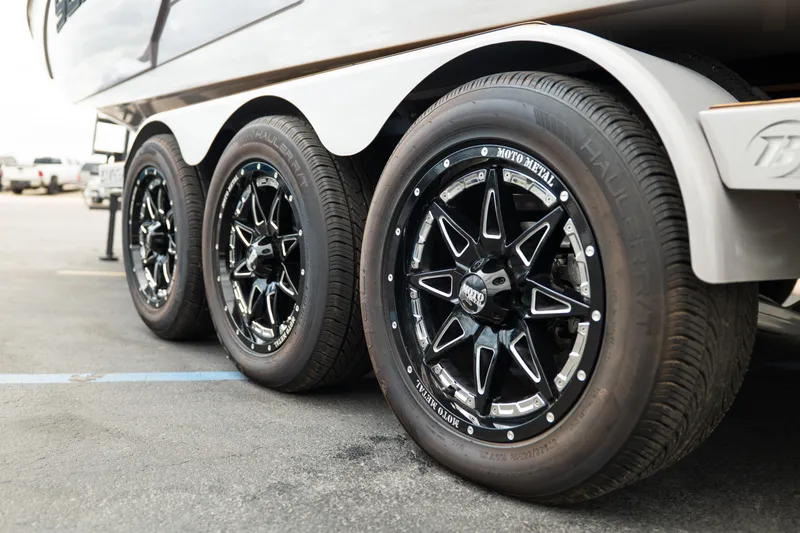 Slide: The Image of 2025 Supra SE 550 trailer with black Moto Metal wheels in a parking lot. - 7