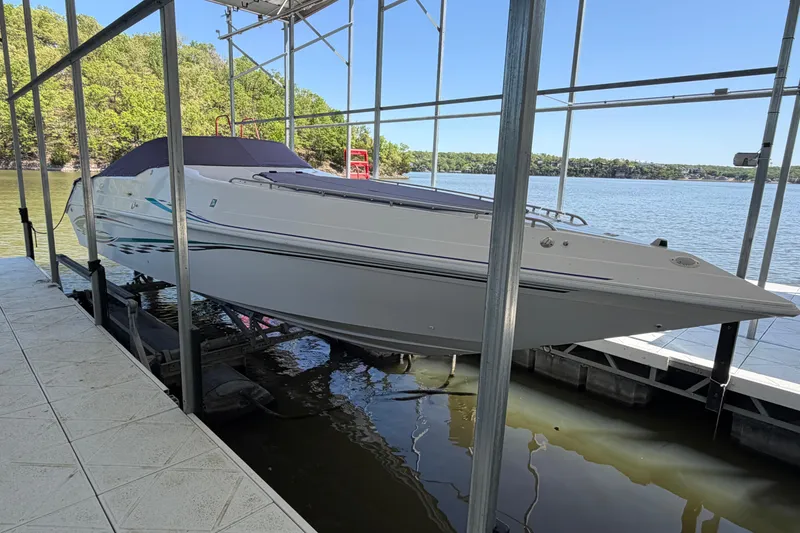 Slide: The Image of 2004 Envision 3200 Intruder boat docked on a lake under a metal canopy. - 2