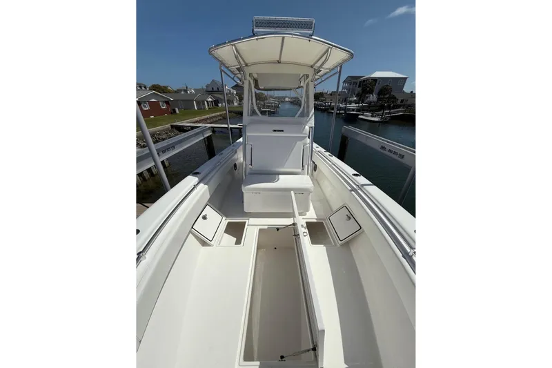 Slide: The Image of 2024 Contender 28 Tournament boat with open deck, storage compartments, and T-top in marina setting. - 3