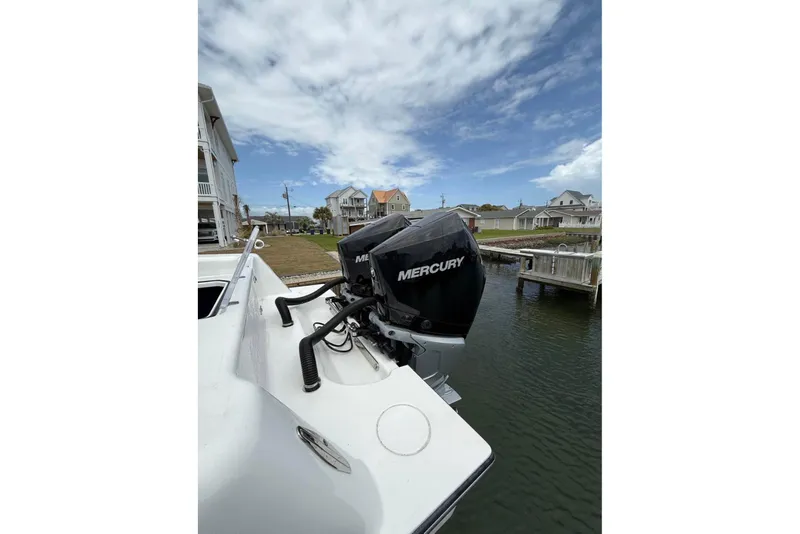 Slide: The Image of 2024 Contender 28 Tournament boat with Mercury outboard motor, docked near waterfront homes. - 6