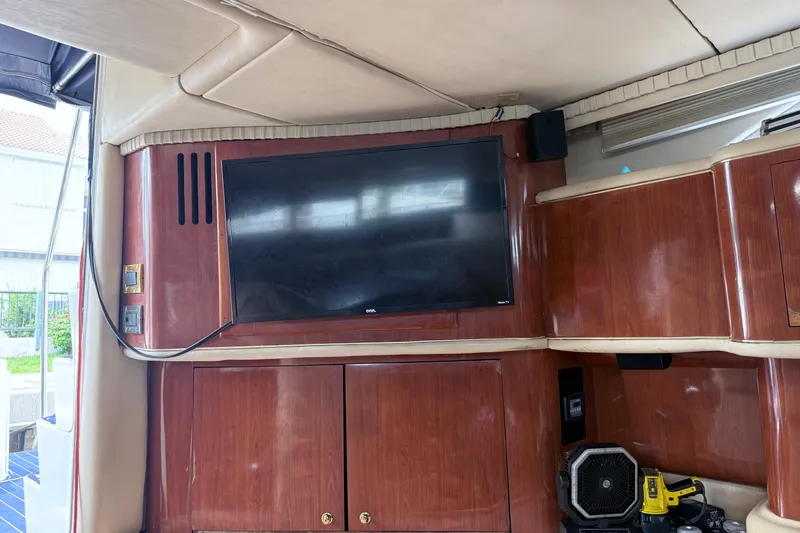 Slide: The Image of Interior of 2001 Sea Ray 450 Express Bridge with mounted TV and wooden cabinetry. - 14