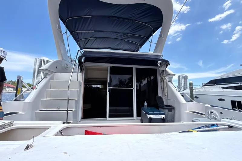 Slide: The Image of 2001 Sea Ray 450 Express Bridge yacht docked, featuring spacious deck and canopy. - 1