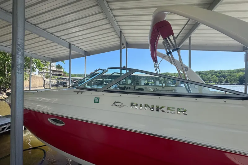 Slide: The Image of 2006 Rinker 282 Captiva Bowrider in dock, red and white exterior, under metal canopy. - 3