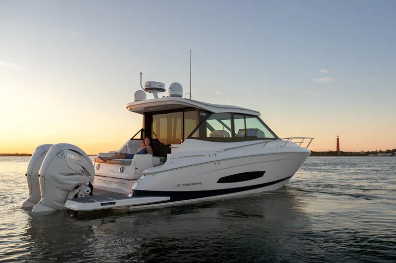 The Image of 2026 Regal 36 XO yacht cruising at sunset with lighthouse in background. - 0