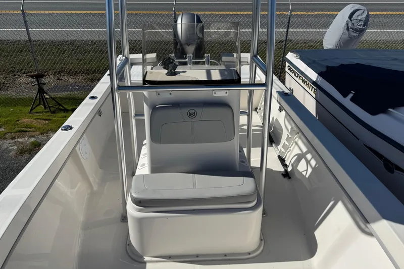 Slide: The Image of 2024 May-Craft 1900CC boat interior with center console and seating, parked near a fence. - 14