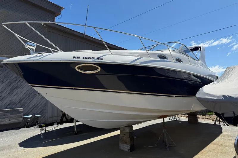 The Image of 2000 Regal Commodore 2960 boat on stands, blue and white hull, sunny day. - 1