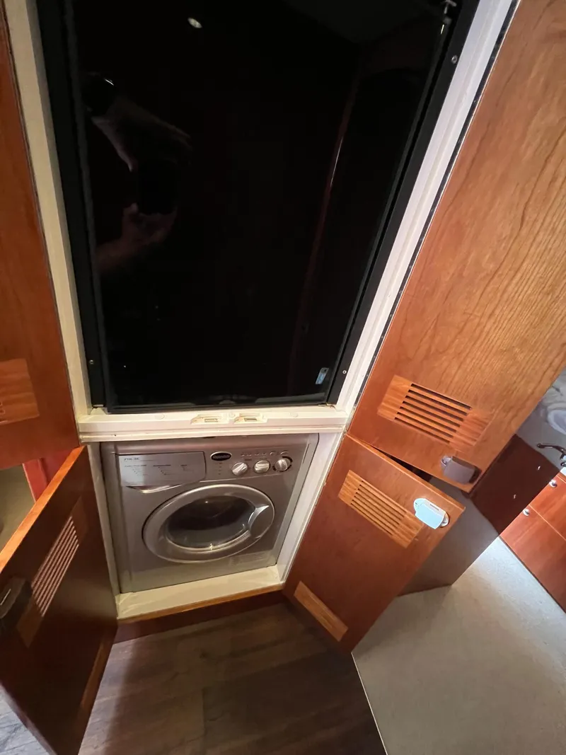 Slide: The Image of Laundry area in 2016 Riviera 45 OPEN yacht with wooden cabinetry and washing machine. - 20