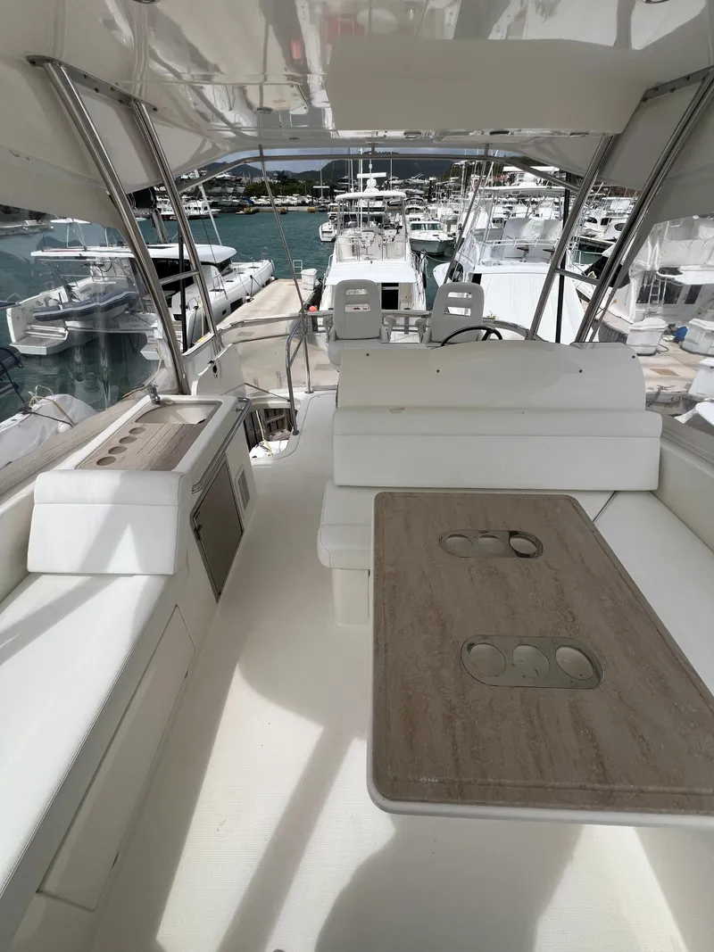 Slide: The Image of 2016 Riviera 45 OPEN yacht interior with seating and table, docked at a marina. - 23