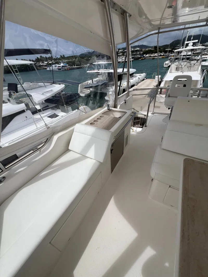 Slide: The Image of 2016 Riviera 45 OPEN yacht interior with marina view, featuring sleek white seating and modern design. - 24