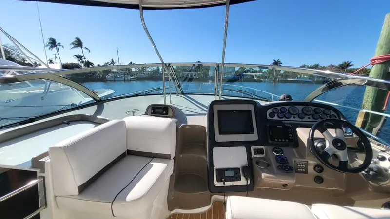 Slide: The Image of 2008 Cruisers 420 Express yacht cockpit with steering wheel, control panel, and seating, docked by palm trees. - 5