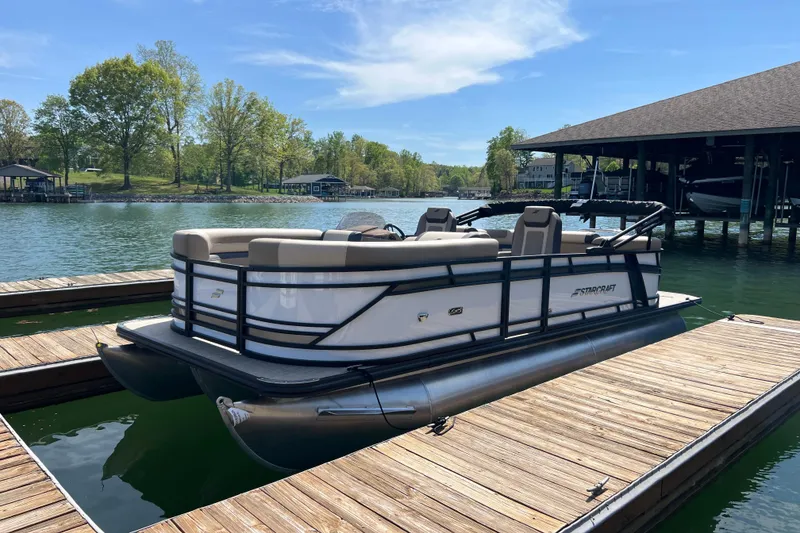 Slide: The Image of 2026 Starcraft EXS 3 R DH pontoon boat docked on a serene lake. - 2