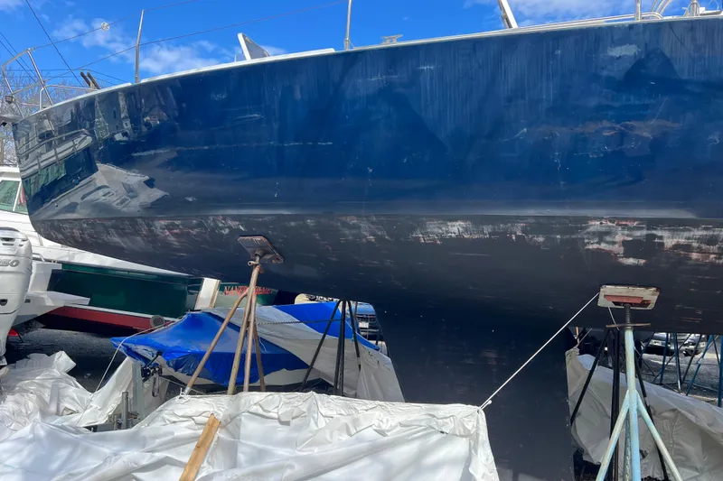 The Image of 1998 J Boats J/120 sailboat on stands, undergoing maintenance, with a blue hull. - 1