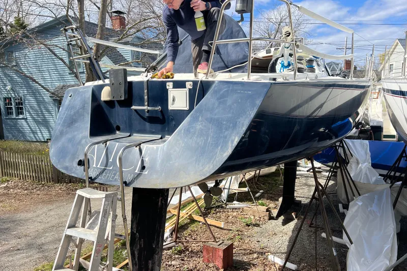 Slide: The Image of Person cleaning a 1998 J Boats J/120 sailboat on land, with ladder and tools nearby. - 4