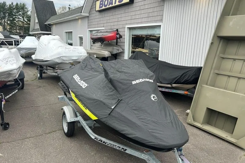 Slide: The Image of 2014 Sea-Doo Wake Pro 215 jet ski covered, parked outside a boat dealership. - 7