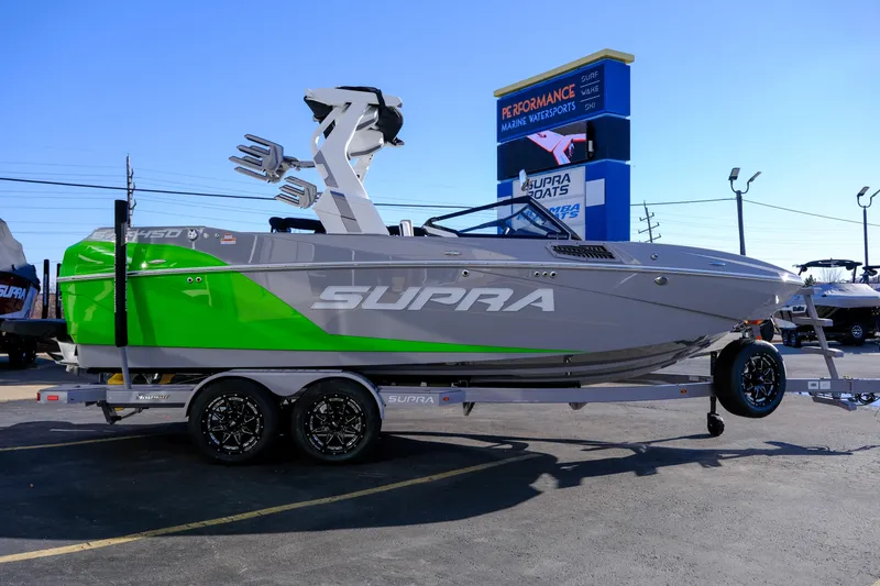 Slide: The Image of 2024 Supra SA 450 boat with green and gray design on a trailer at a dealership. - 5