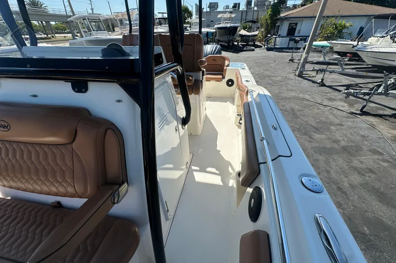 Slide: The Image of 2021 Key West 263 FS boat interior with brown seating, docked outdoors. - 17