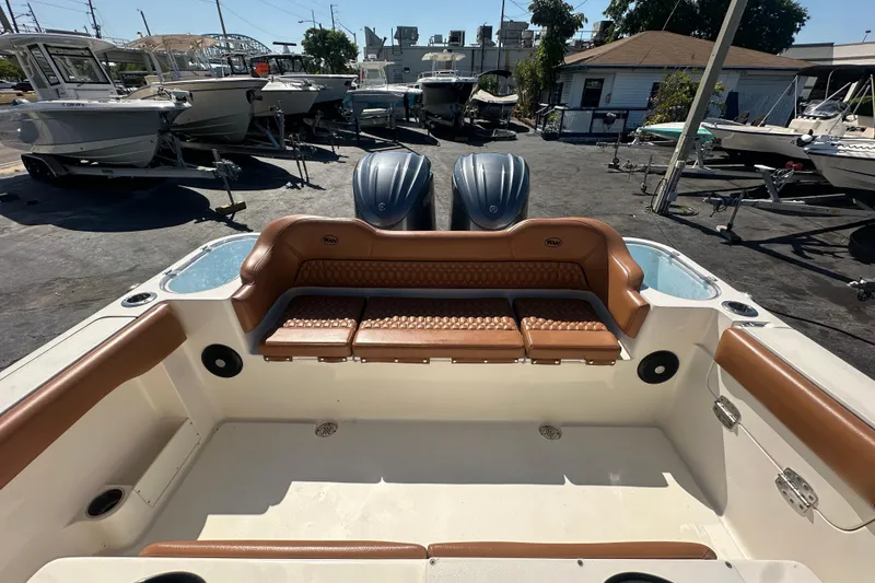 Slide: The Image of 2021 Key West 263 FS boat interior with brown seating and dual engines in a marina. - 29