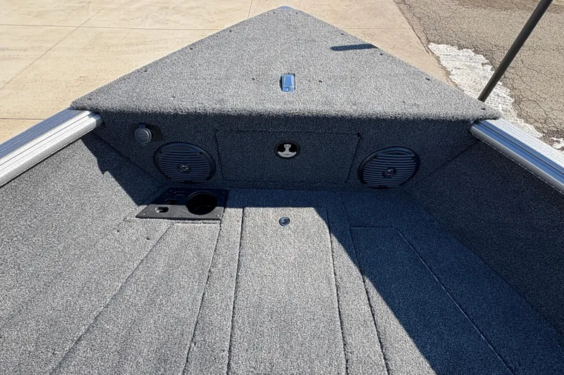 Slide: The Image of 2026 Lund 1875 Impact XS Sport boat interior with carpeted deck and speakers. - 13