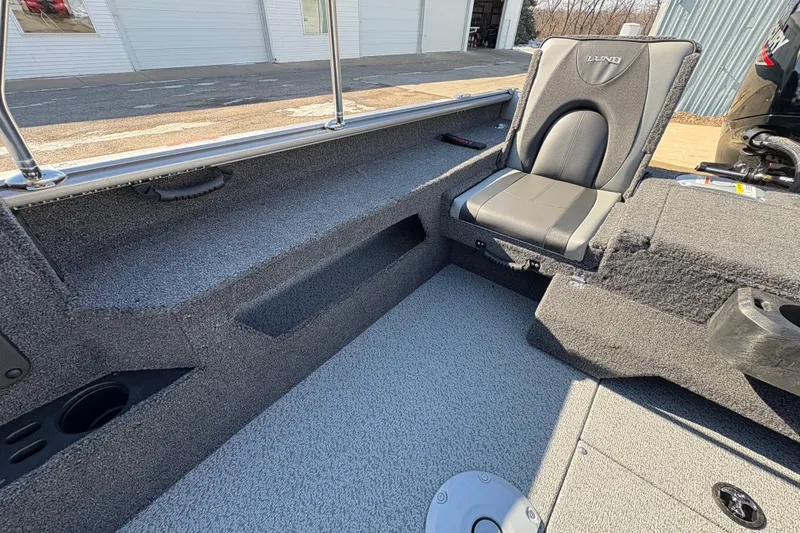 Slide: The Image of 2026 Lund 1875 Impact XS Sport boat interior with gray seating and carpeted flooring. - 25